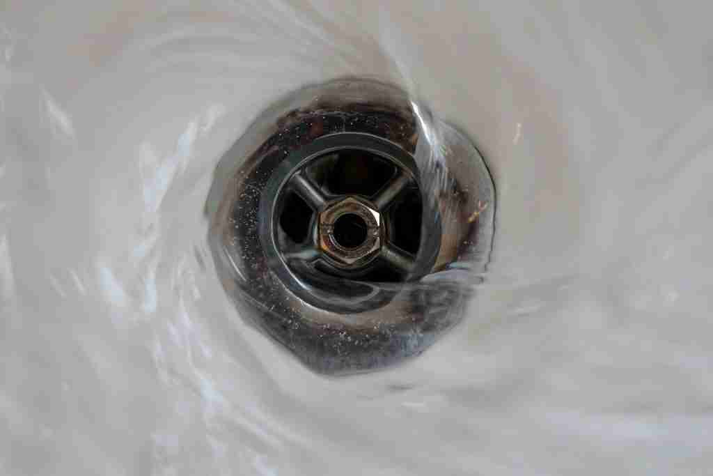 Close-up of water swirling into a drain pipe.